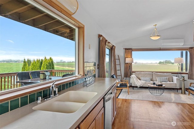 kitchen with dishwasher, vaulted ceiling, a wall unit AC, a rural view, and sink