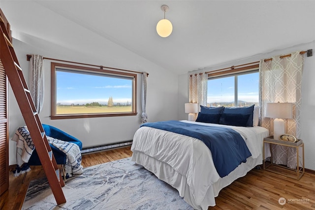 bedroom with baseboard heating, multiple windows, vaulted ceiling, and hardwood / wood-style floors