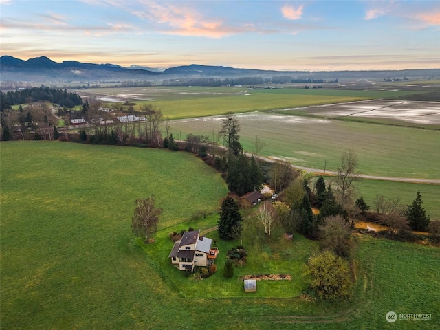 aerial view at dusk featuring a rural view and a mountain view