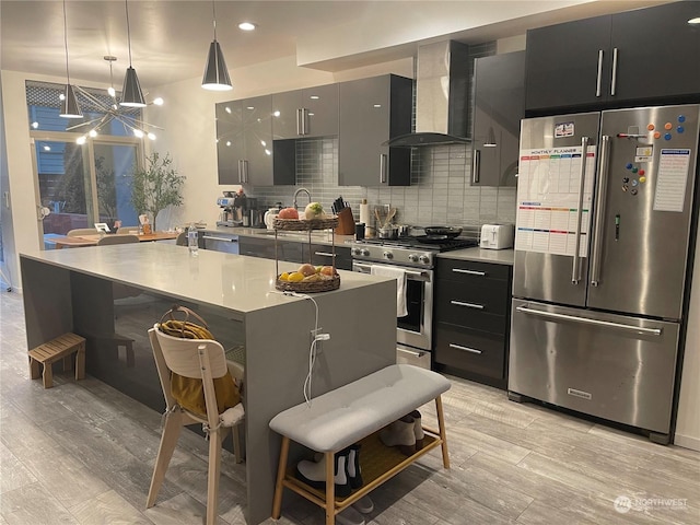 kitchen with decorative light fixtures, decorative backsplash, wall chimney range hood, a breakfast bar, and appliances with stainless steel finishes