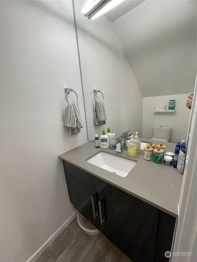 bathroom with lofted ceiling, vanity, and toilet