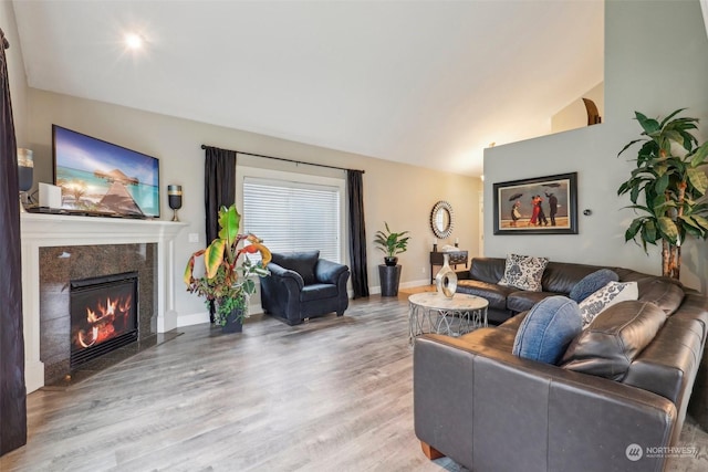 living room with hardwood / wood-style flooring, a premium fireplace, and lofted ceiling