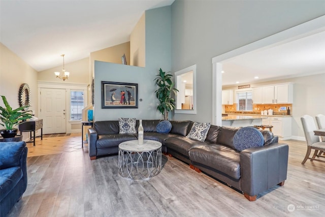 living room featuring a chandelier, vaulted ceiling, and light wood-type flooring