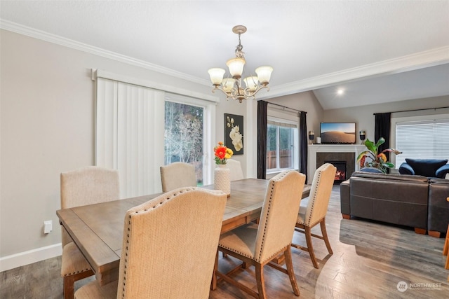 dining space with a wealth of natural light, vaulted ceiling, hardwood / wood-style floors, and a notable chandelier