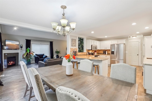 dining area with a notable chandelier, light hardwood / wood-style flooring, and ornamental molding