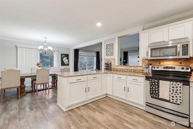 kitchen featuring white cabinetry, stainless steel appliances, kitchen peninsula, and an inviting chandelier