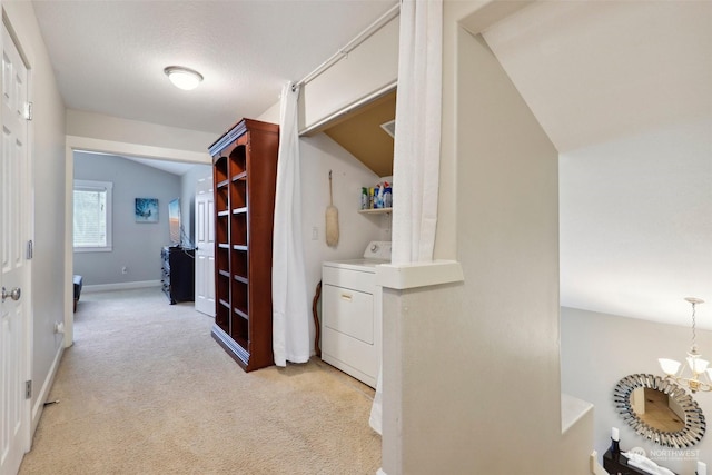 hall featuring lofted ceiling, a textured ceiling, light carpet, washer / dryer, and a chandelier