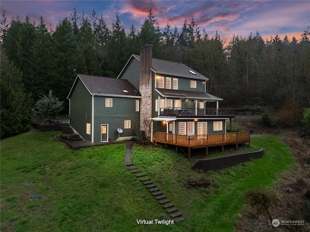 back house at dusk featuring a yard and a deck