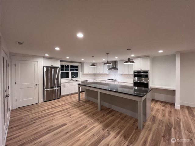 kitchen with sink, a center island, white cabinetry, hanging light fixtures, and appliances with stainless steel finishes