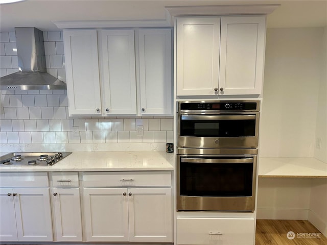 kitchen featuring decorative backsplash, gas cooktop, white cabinetry, and ventilation hood