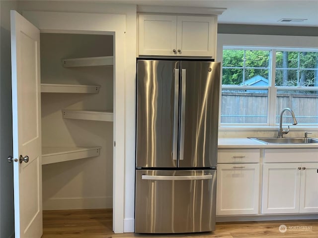 kitchen featuring sink, white cabinets, and stainless steel refrigerator