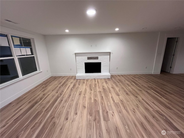 unfurnished living room with a fireplace and light hardwood / wood-style floors