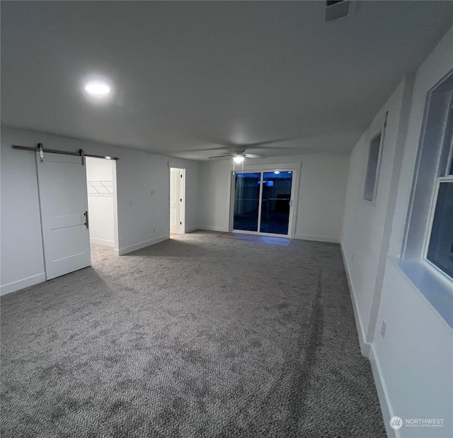 unfurnished room with ceiling fan, a barn door, and carpet floors