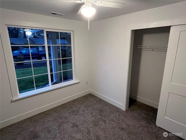 unfurnished bedroom featuring dark carpet, a closet, and ceiling fan