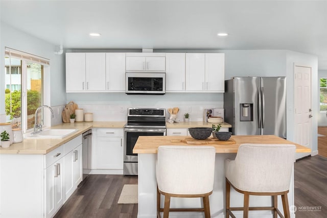 kitchen featuring appliances with stainless steel finishes, butcher block counters, sink, white cabinets, and dark hardwood / wood-style flooring