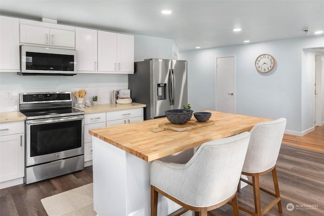 kitchen with white cabinetry, appliances with stainless steel finishes, a kitchen breakfast bar, and a kitchen island