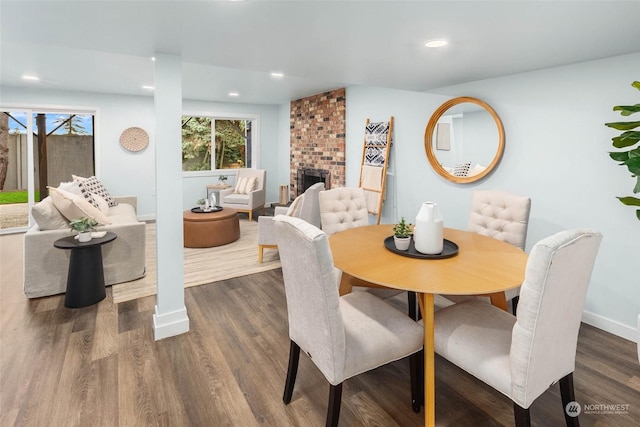 dining area with dark wood-type flooring and a fireplace