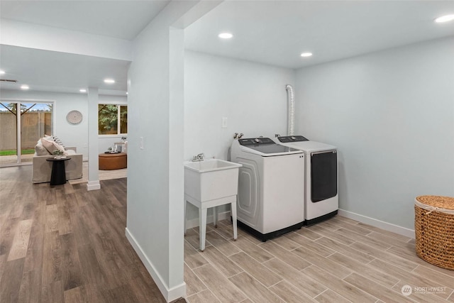 clothes washing area with washer and clothes dryer and light hardwood / wood-style floors