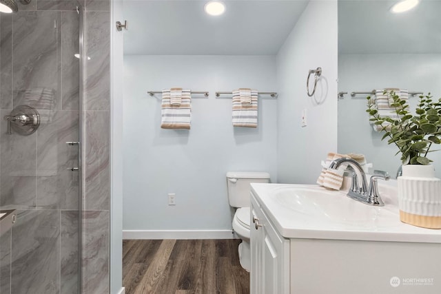 bathroom with hardwood / wood-style flooring, vanity, toilet, and a shower with door