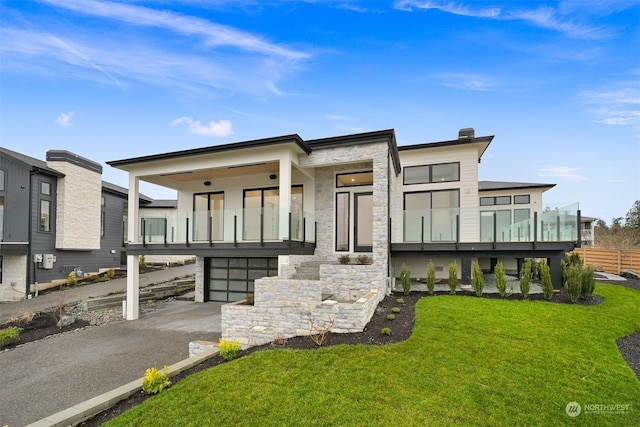 contemporary home featuring a front lawn, a balcony, an attached garage, and stone siding