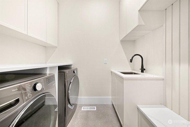 laundry room with visible vents, baseboards, washing machine and dryer, cabinet space, and a sink