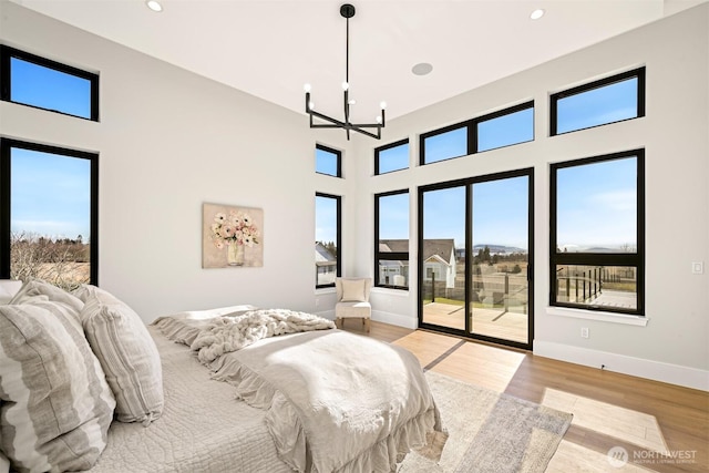 bedroom with an inviting chandelier, access to outside, multiple windows, and light wood finished floors