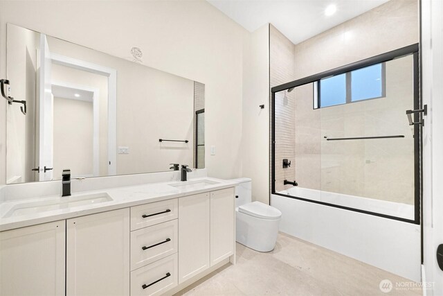 bathroom with a sink, combined bath / shower with glass door, toilet, and double vanity