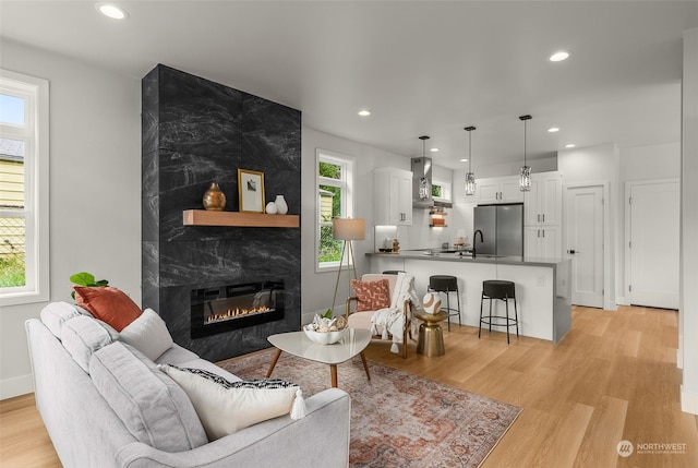 living room with a high end fireplace and light wood-type flooring