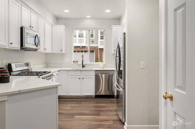 kitchen featuring stainless steel appliances, sink, white cabinetry, light stone countertops, and dark hardwood / wood-style floors