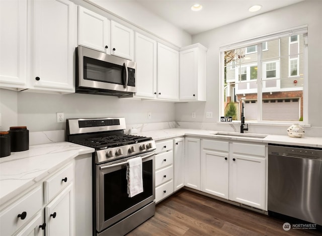 kitchen featuring light stone countertops, dark hardwood / wood-style floors, white cabinets, appliances with stainless steel finishes, and sink