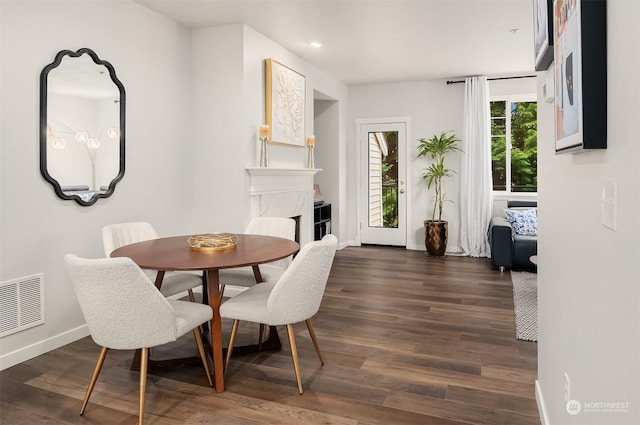 dining room featuring a high end fireplace and dark hardwood / wood-style floors