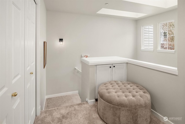 living area featuring light colored carpet and a skylight