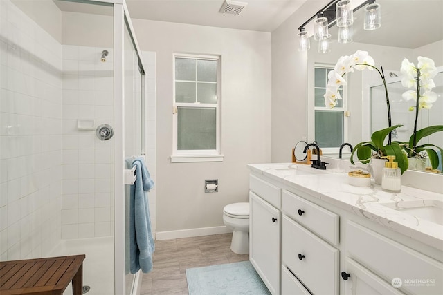 bathroom featuring toilet, tile patterned flooring, walk in shower, and vanity