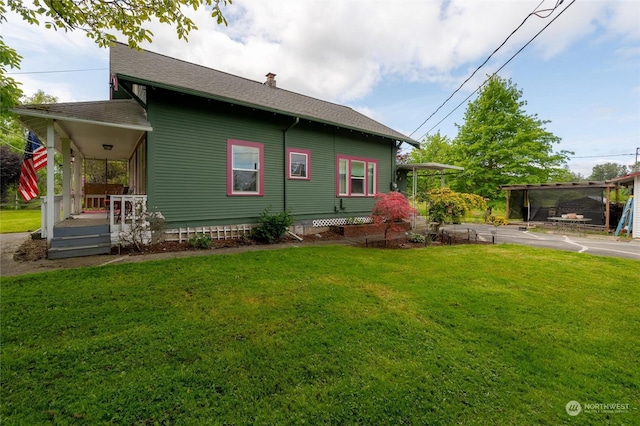 view of side of home featuring a yard and covered porch