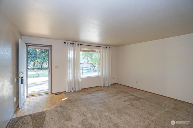 unfurnished room featuring light parquet floors and a healthy amount of sunlight