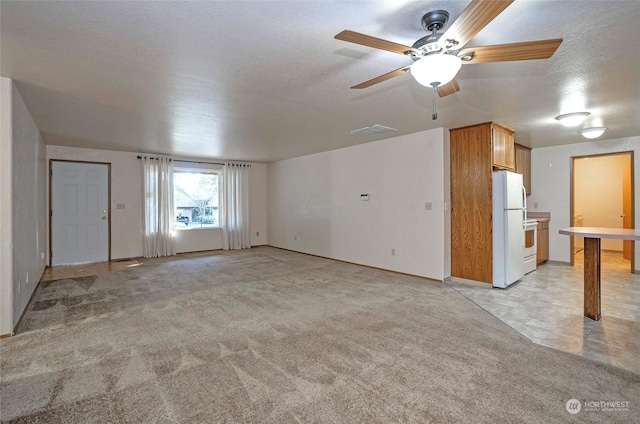 unfurnished living room featuring ceiling fan and light carpet