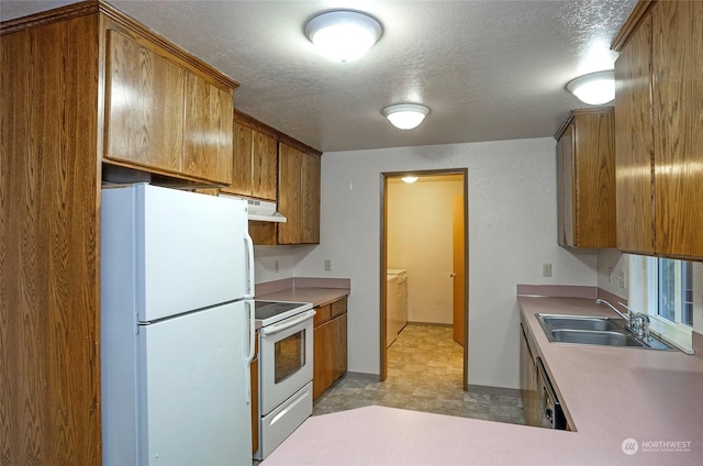 kitchen with washer and clothes dryer, sink, a textured ceiling, and white appliances