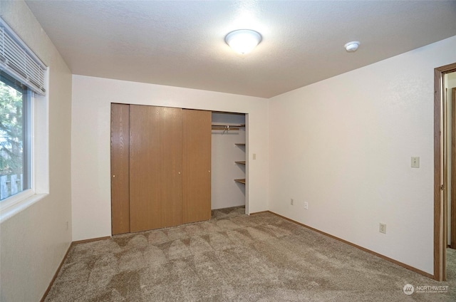 unfurnished bedroom with light colored carpet and a closet