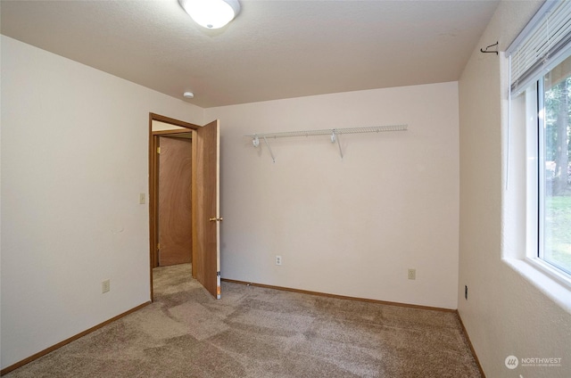 unfurnished bedroom featuring light colored carpet and a closet