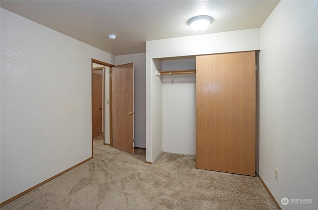 unfurnished bedroom with light colored carpet and a closet