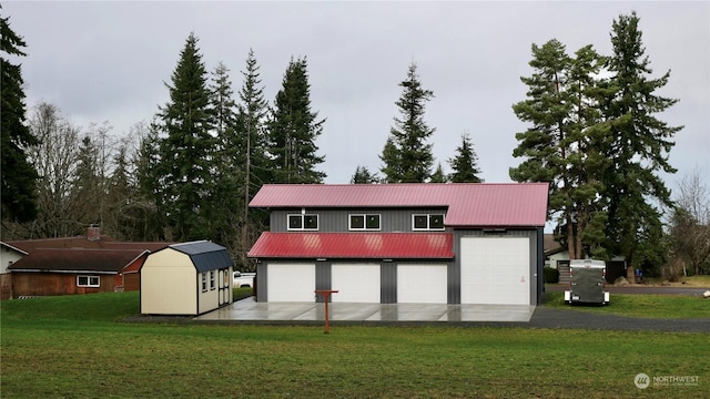 rear view of property featuring a yard, a shed, and a garage