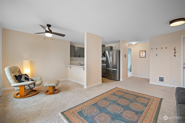 living area featuring ceiling fan, light colored carpet, and sink