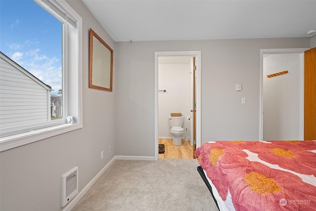 bedroom with ensuite bath and light colored carpet