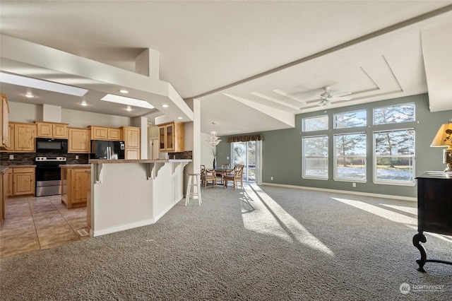 kitchen with a kitchen island, a breakfast bar, tasteful backsplash, black appliances, and light brown cabinets