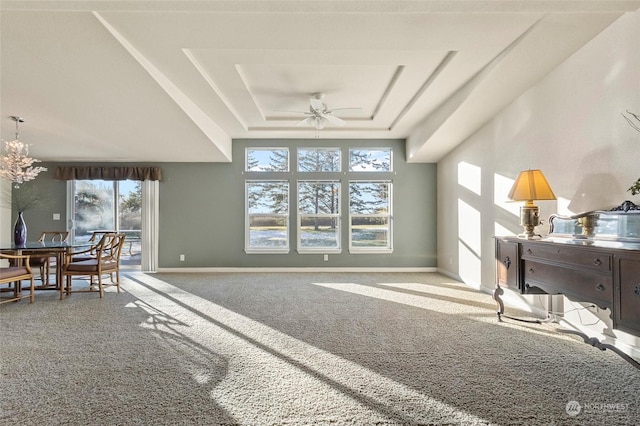 carpeted living room featuring ceiling fan with notable chandelier and a tray ceiling