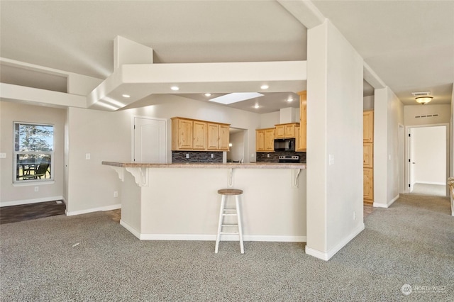 kitchen with a kitchen breakfast bar, kitchen peninsula, light carpet, and light brown cabinets