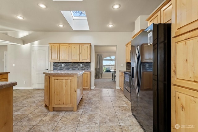 kitchen with black fridge, a center island, light brown cabinetry, and electric stove