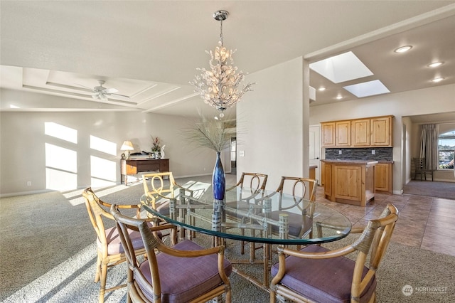 carpeted dining area featuring a raised ceiling and ceiling fan with notable chandelier