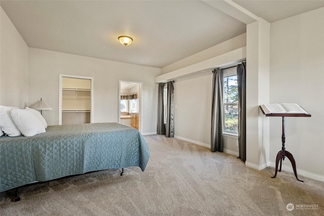 carpeted bedroom with ensuite bathroom and a spacious closet