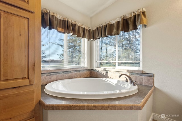 bathroom featuring vaulted ceiling and tiled bath